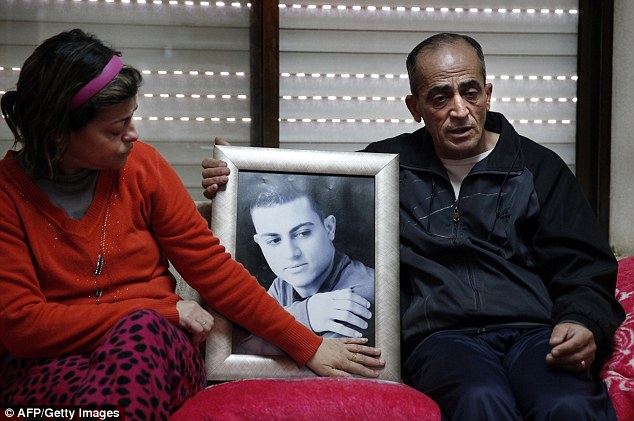 The parents of Israeli-Arab Muhammad Musallam sit next to a framed portrait of their son, who was captured by ISIS for allegedly spying for Mossad