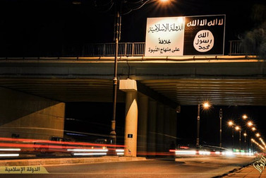 The Islamic State’s flag hangs from a bridge in Mosul, Iraq.